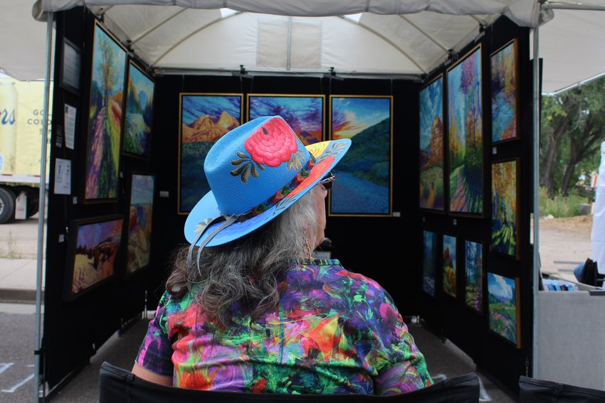 Daniela Bogart sits outside her husband's booth during the Golden Fine Arts Festival Aug. 20 along 11th Street downtown. Darien Bogart is a painter based in Las Cruces, New Mexico.